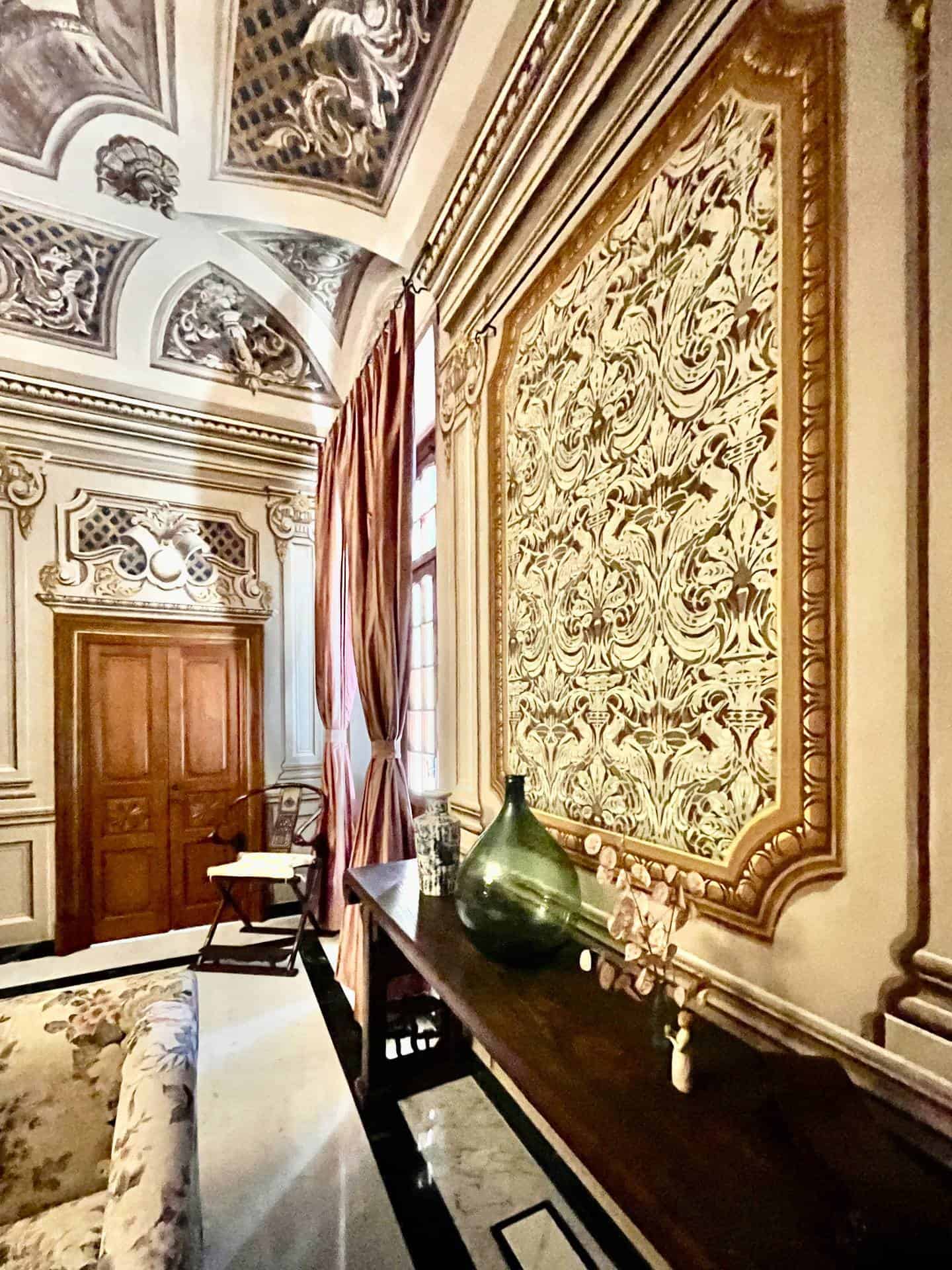 Elegant historic interior with ornate wall decor and classic furnishings.