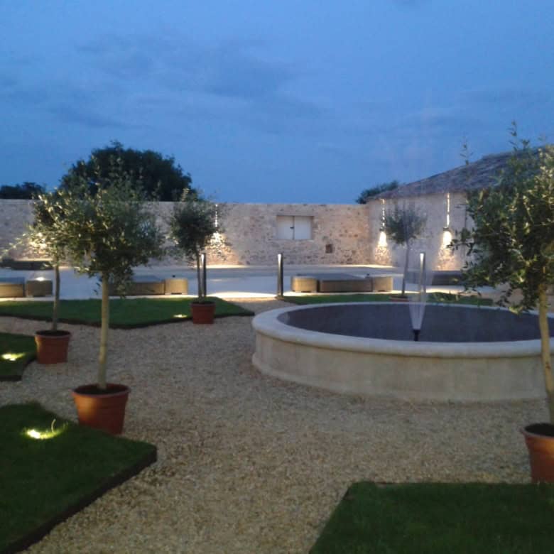Elegant estate garden with potted trees and a central fountain in Goudargues, France.