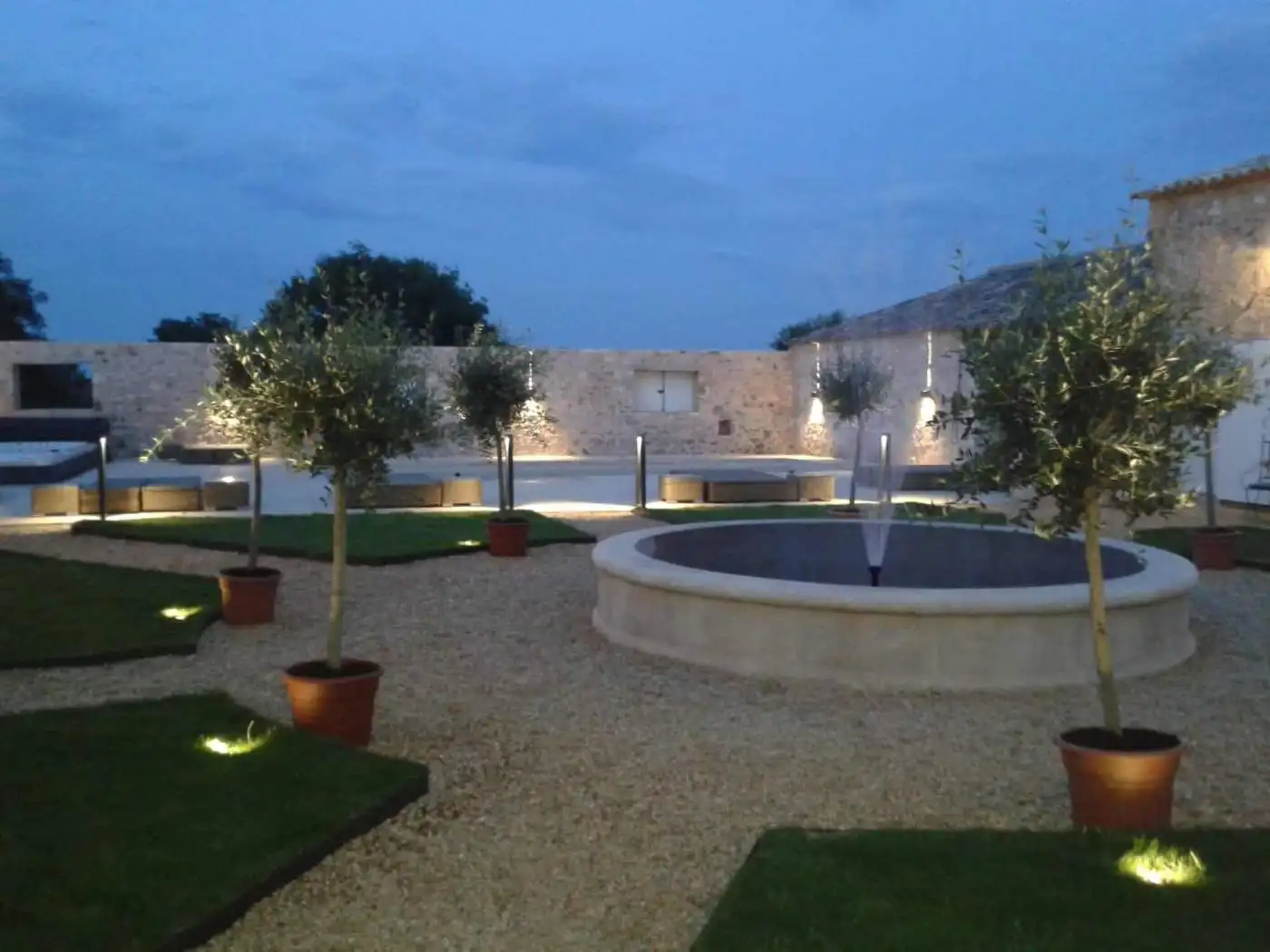 Elegant estate garden with potted trees and a central fountain in Goudargues, France.