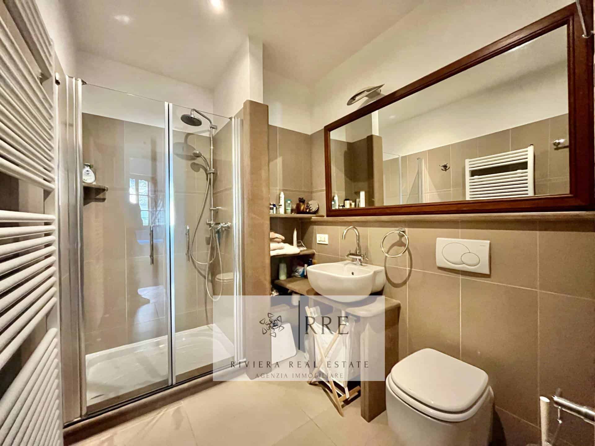 Contemporary bathroom featuring a glass shower enclosure, large mirror, and modern fixtures.