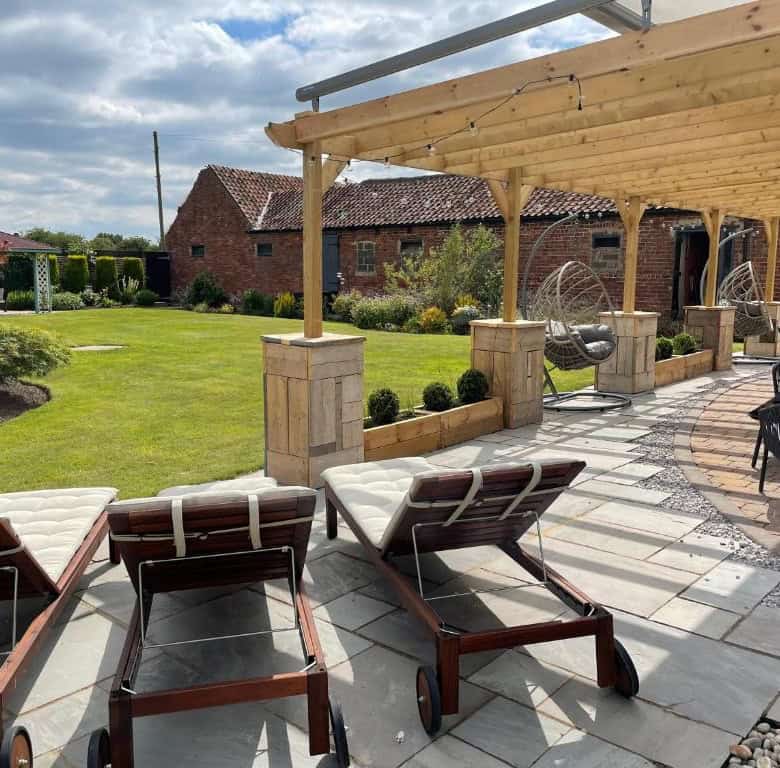 Outdoor patio with lounge chairs, pergola, and lush garden setting.