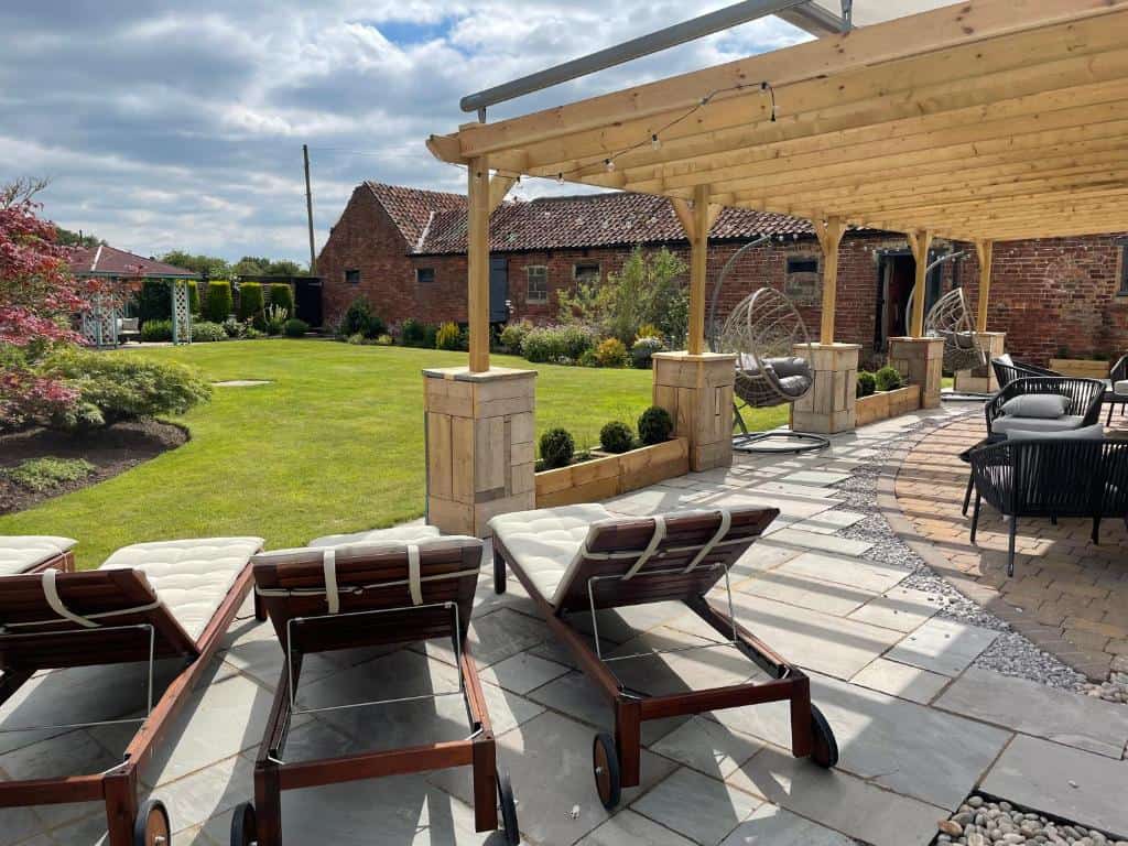 Modern outdoor patio with lounge chairs and garden view Outdoor patio with lounge chairs, pergola, and lush garden setting.