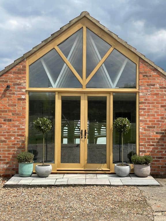 Elegant glass entrance with wooden framing and triangular window design.