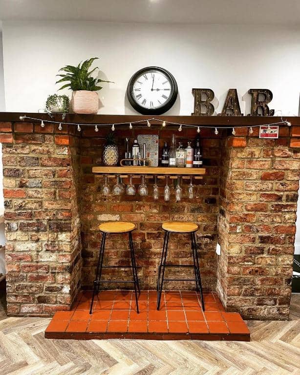 Home bar with brick arch, shelves, and stools for a cozy entertainment space.