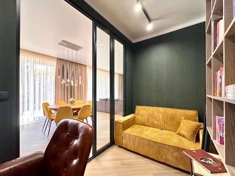 Bright interior featuring a yellow sofa and a dark accent wall in a contemporary apartment.