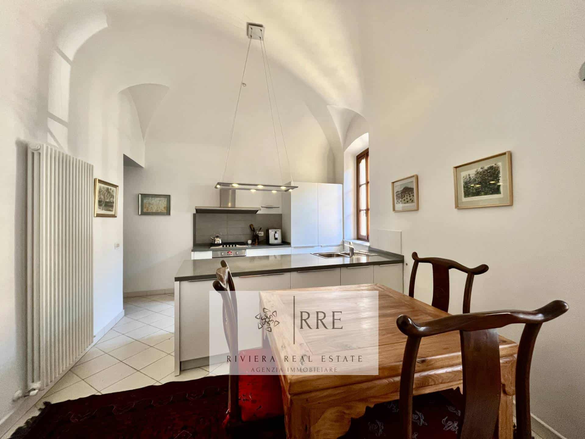 Bright kitchen with white walls, wooden dining table, and natural light.