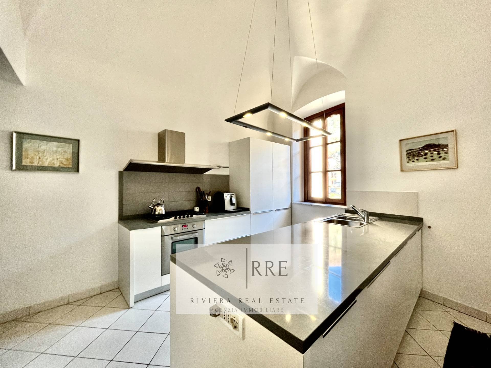 Modern kitchen with white cabinets, black countertops, and a large window providing natural light.