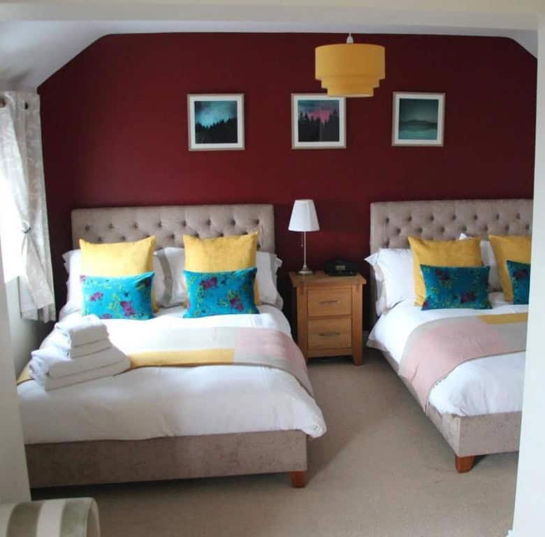 A modern hotel bedroom featuring two beds with vibrant pillows and a stylish interior design.