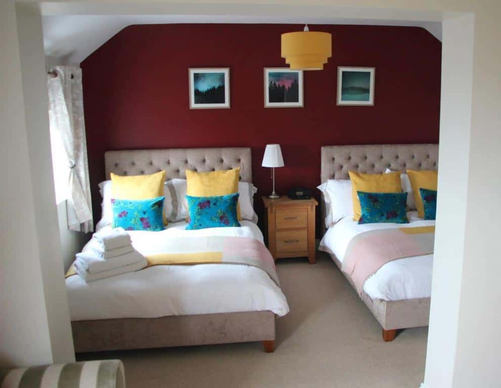 Modern hotel bedroom with two beds and colorful pillows. A modern hotel bedroom featuring two beds with vibrant pillows and a stylish interior design.
