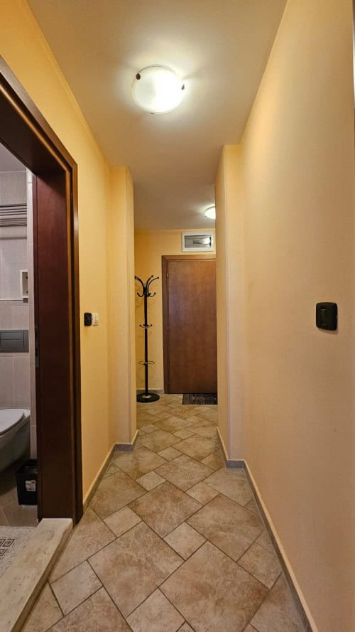 Cozy hallway in apartment building Interior view of a hallway in a modern apartment with warm yellow walls and tiled flooring.