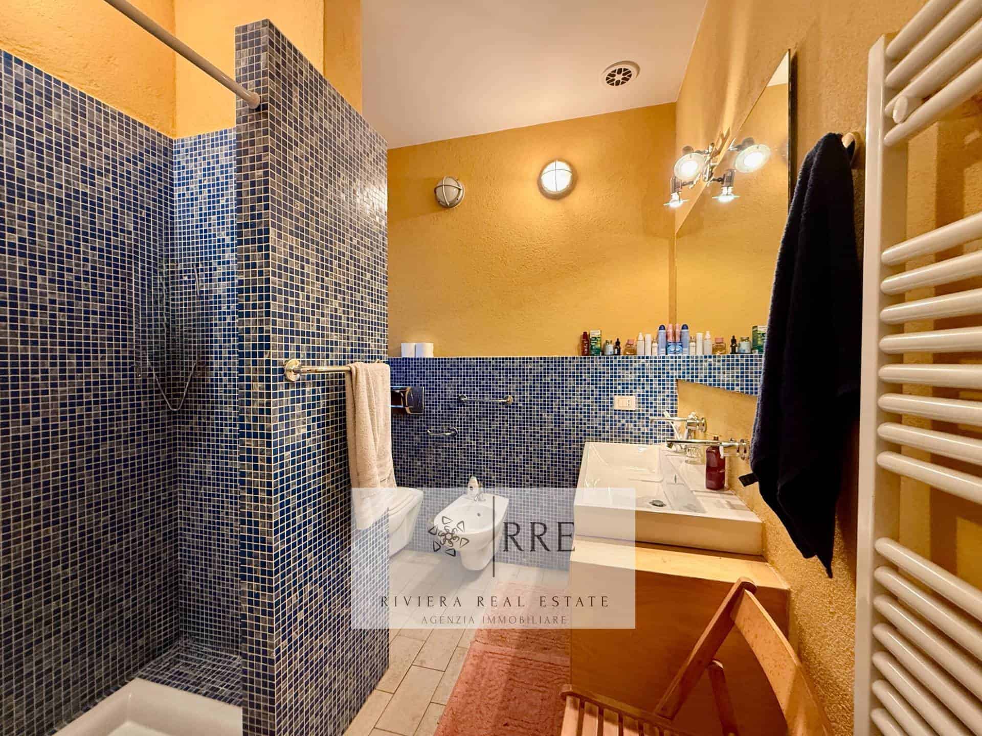 Bathroom with blue mosaic tiles, beige walls, and modern fixtures.