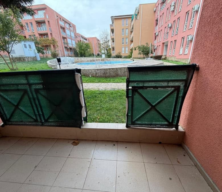 Bright balcony view of the apartment with access to a shared pool and green courtyard.