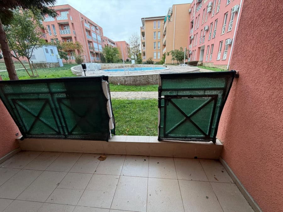 Bright balcony view of the apartment with access to a shared pool and green courtyard.