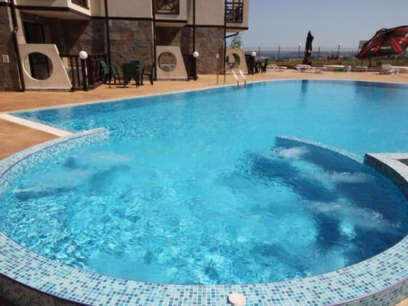 Bright outdoor swimming pool with surrounding sun loungers and umbrellas at Imperial Heights, Sunny.