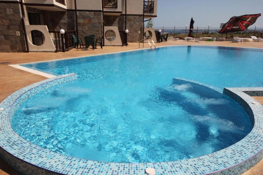 Bright outdoor swimming pool with surrounding sun loungers and umbrellas at Imperial Heights, Sunny.