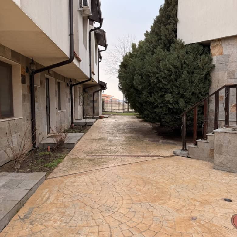 Modern apartment building exterior with paved walkway and greenery.