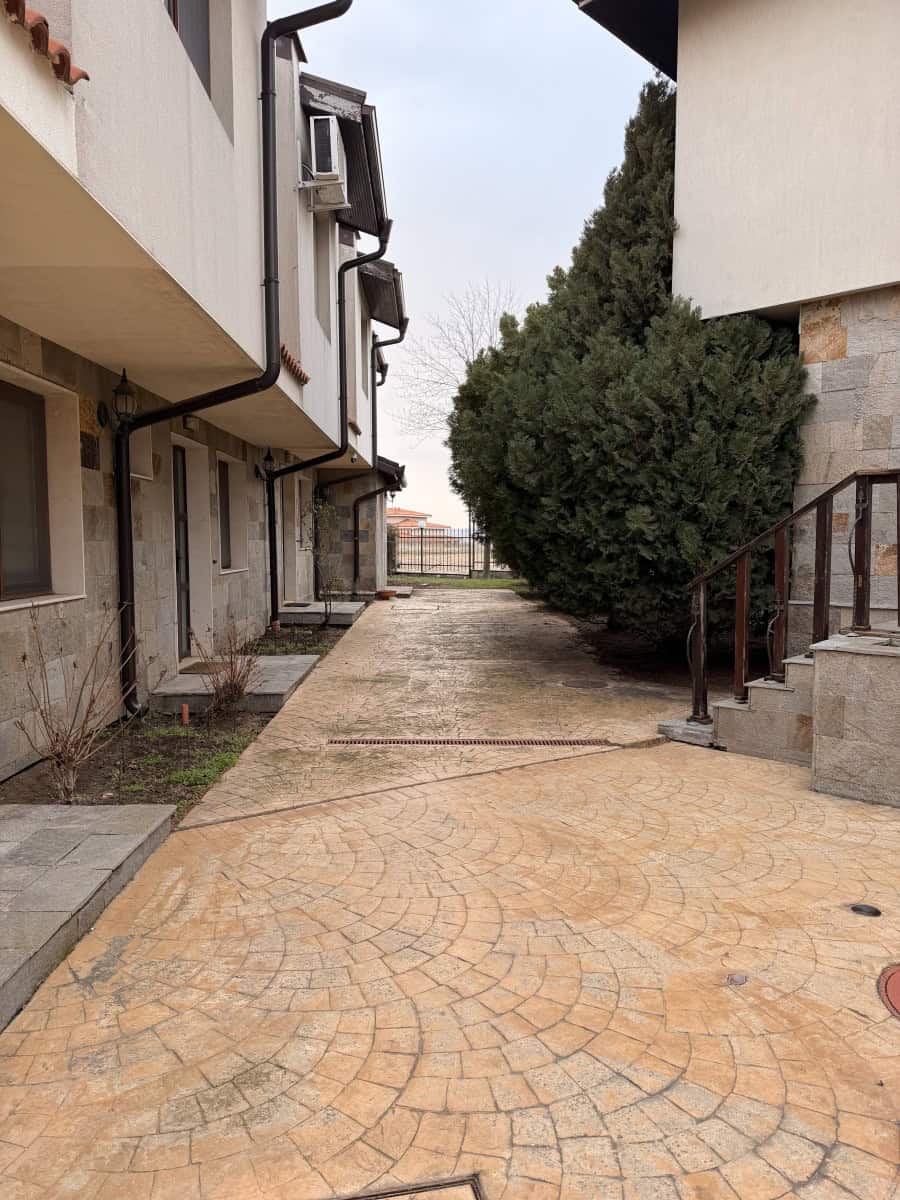 Modern apartment building exterior with paved walkway and greenery Modern apartment building exterior with paved walkway and greenery.