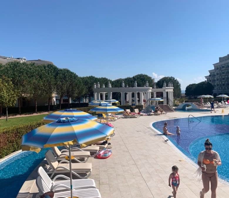 Poolside view of Sunset Resort in Pomorie with sun loungers and umbrellas.
