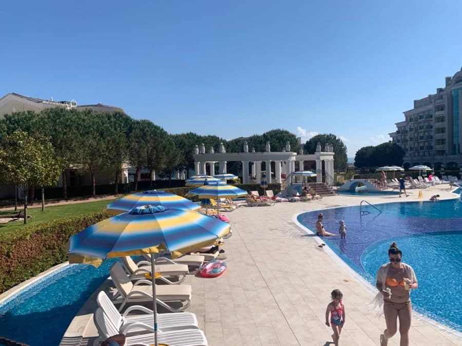 Poolside view of Sunset Resort in Pomorie with sun loungers and umbrellas.