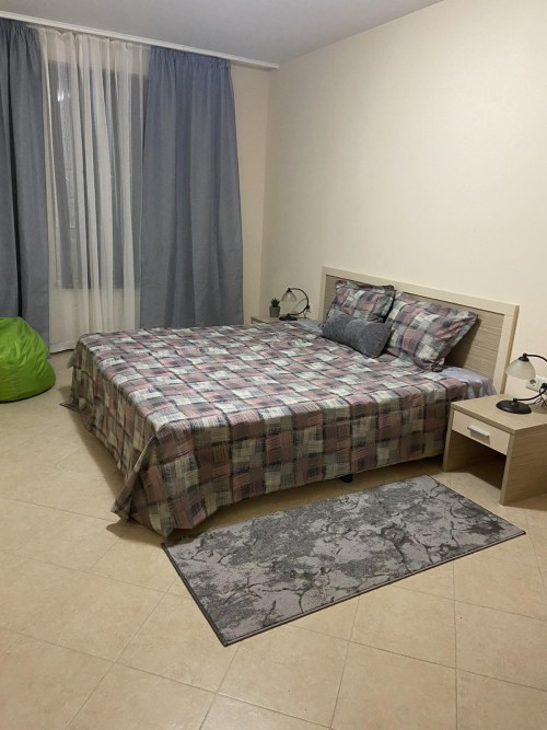 Interior of a 1-bedroom apartment with a large bed, nightstands, and view to the surroundings in Sun.