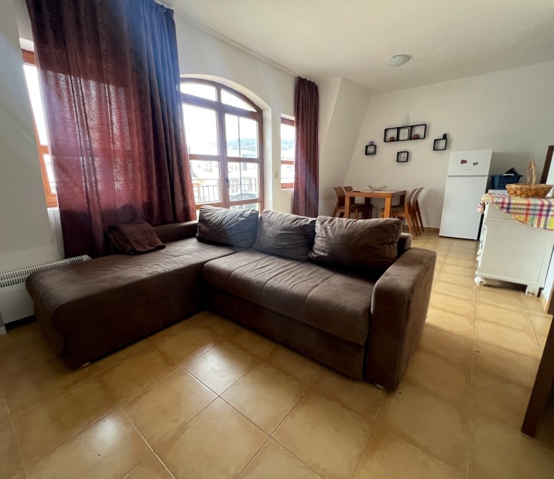 Spacious living area featuring a large sofa, natural light, and scenic mountain views from the windo.
