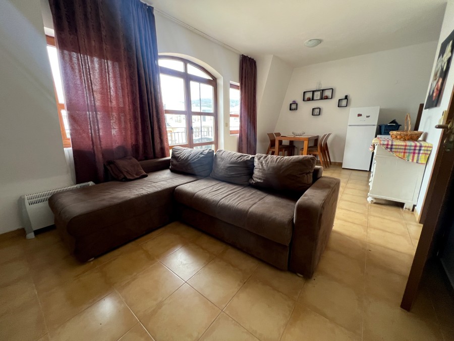 Spacious living area featuring a large sofa, natural light, and scenic mountain views from the windo.