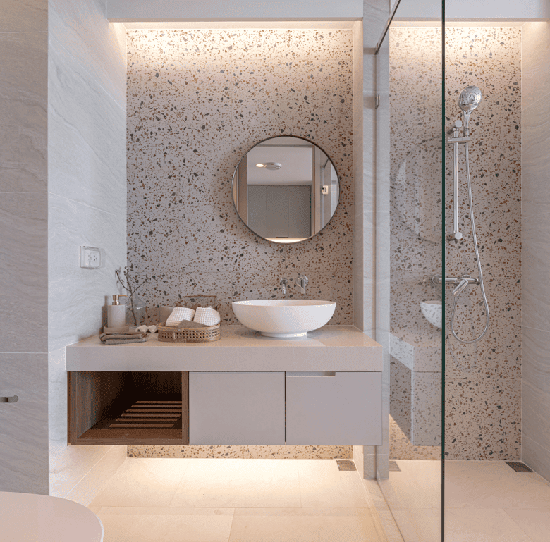 Elegant bathroom featuring a round mirror, vessel sink, and glass-enclosed shower.