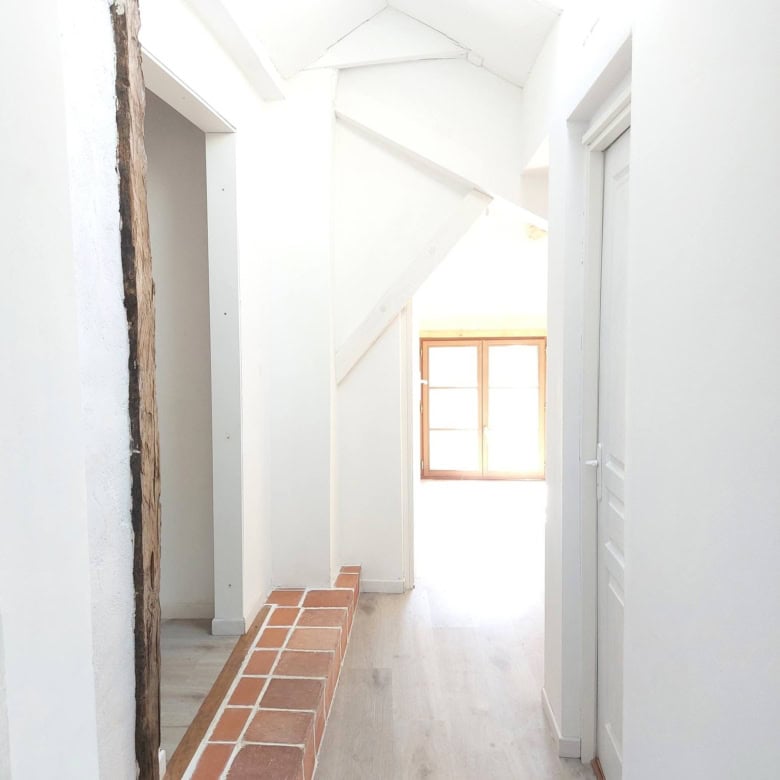 Bright farmhouse hallway with white walls and natural light in Madiran village, France.