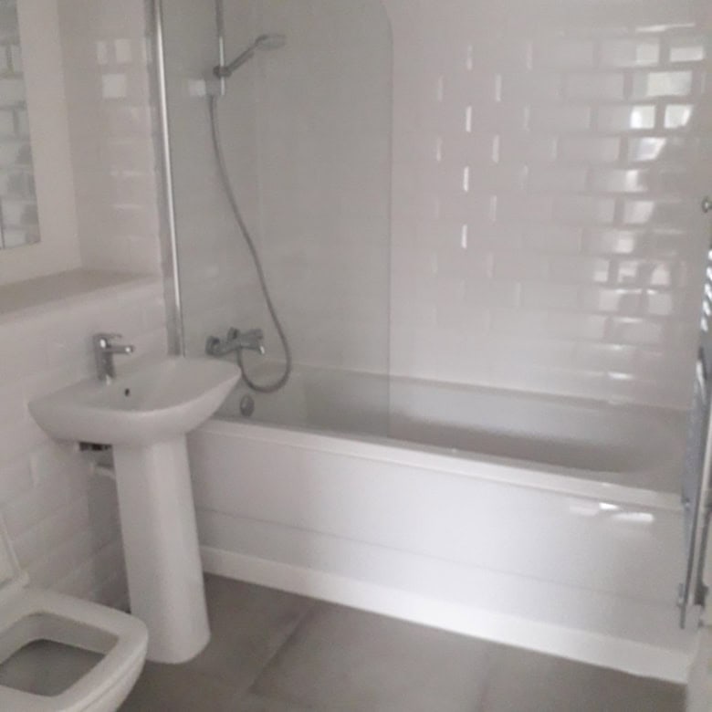 Bright bathroom featuring a bathtub, sink, and toilet in a contemporary Birmingham apartment.
