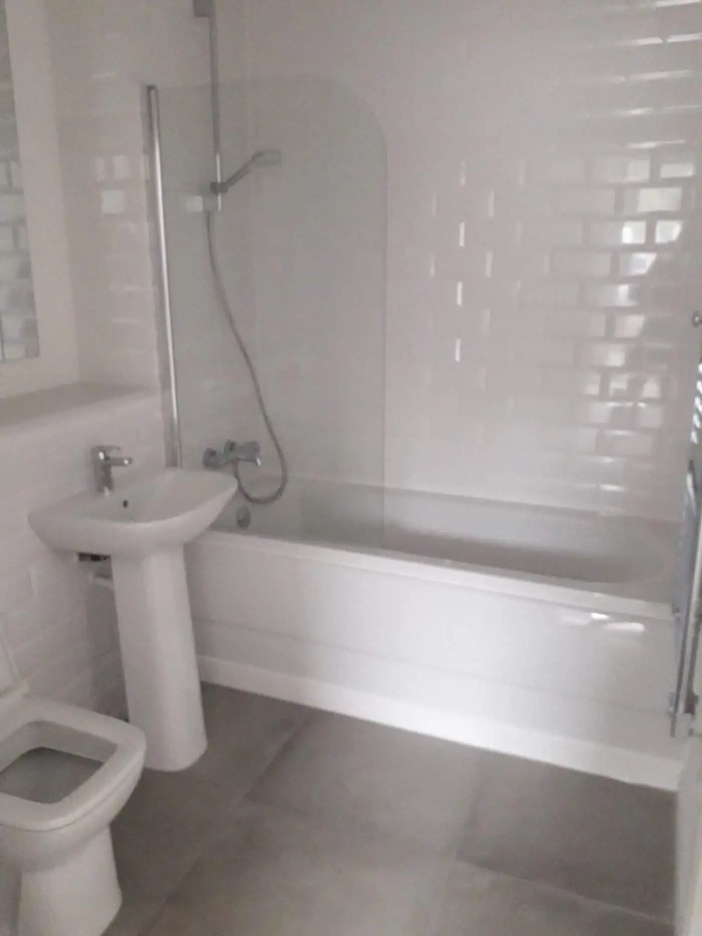 Bright bathroom featuring a bathtub, sink, and toilet in a contemporary Birmingham apartment.