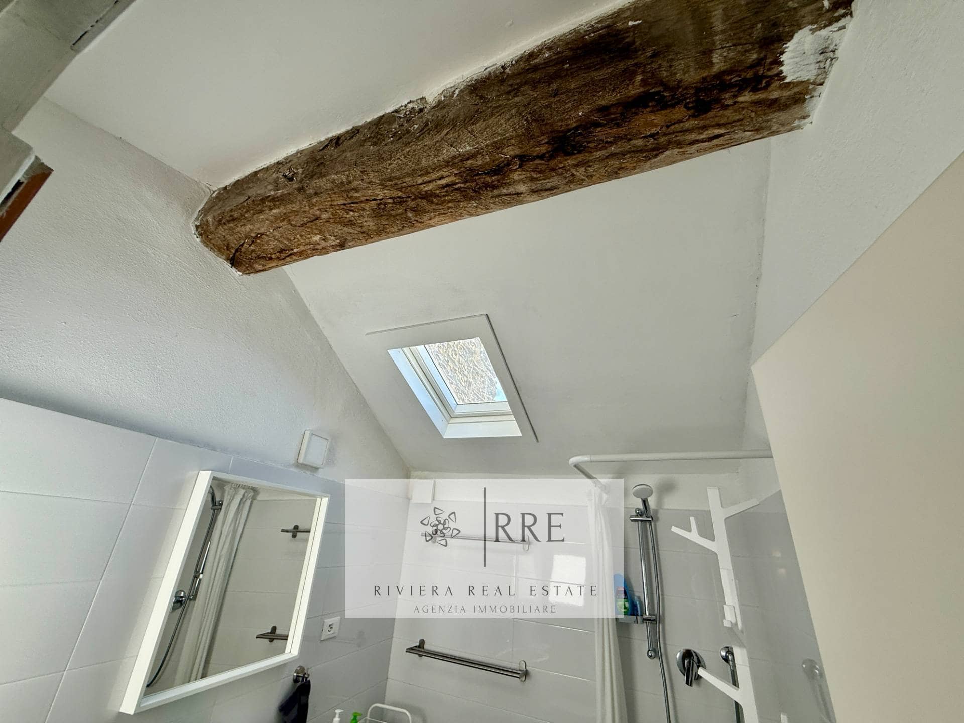 Attic apartment featuring a skylight, exposed wooden beam, and contemporary interior design.