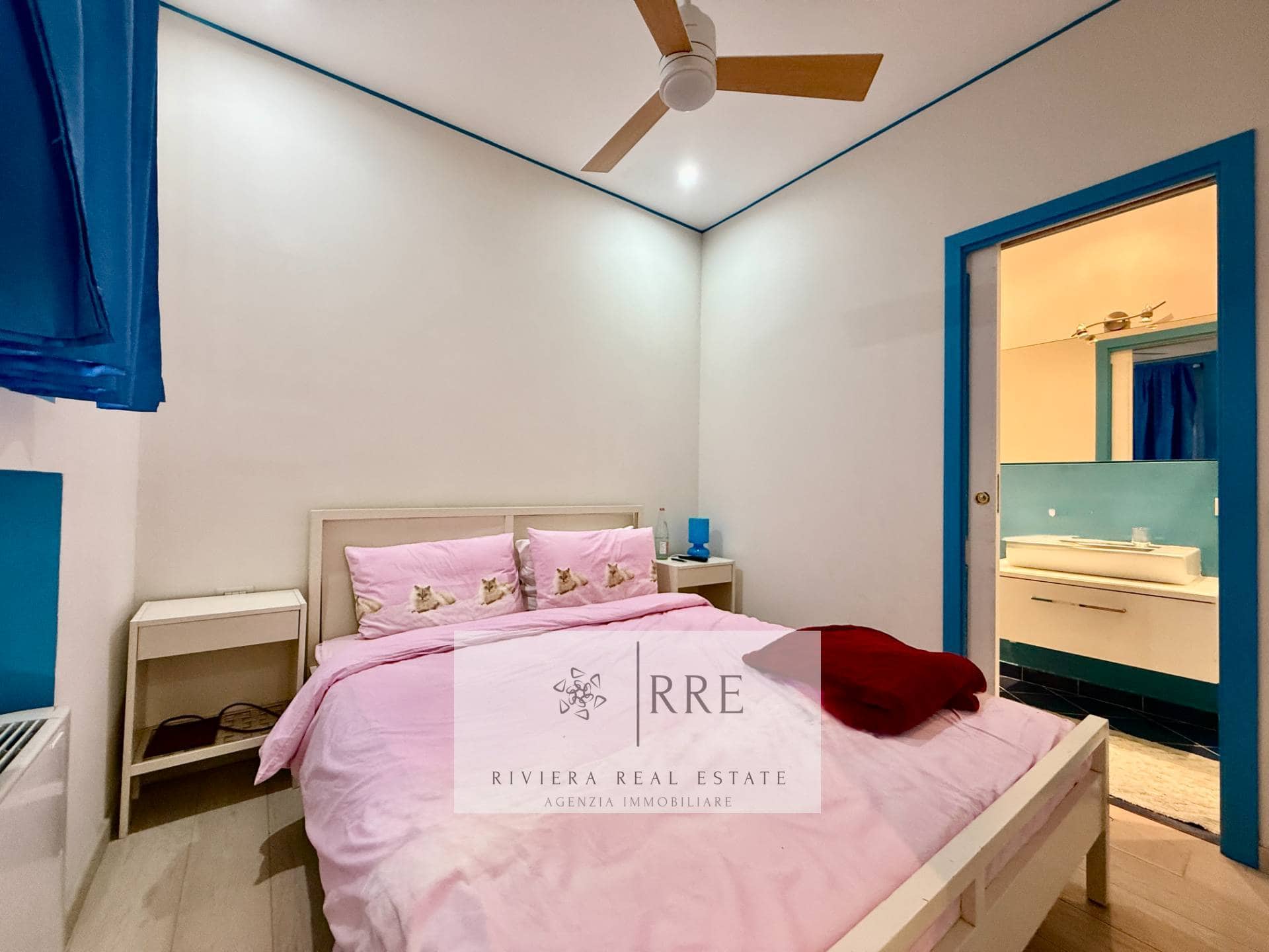Cozy bedroom featuring pink bedding, a ceiling fan, and blue window and door frames.