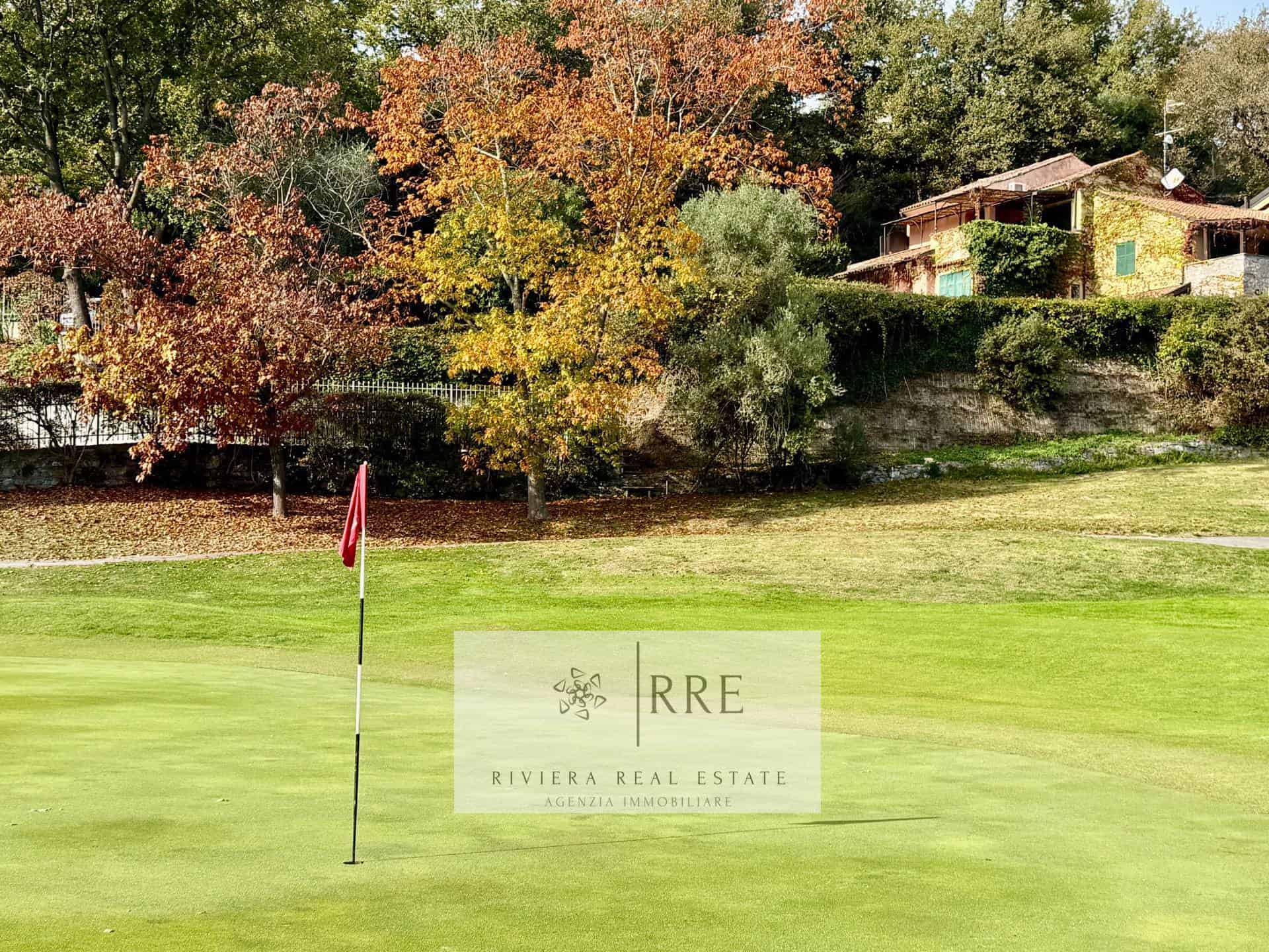 Golf course with colorful autumn trees and residential houses in the background.