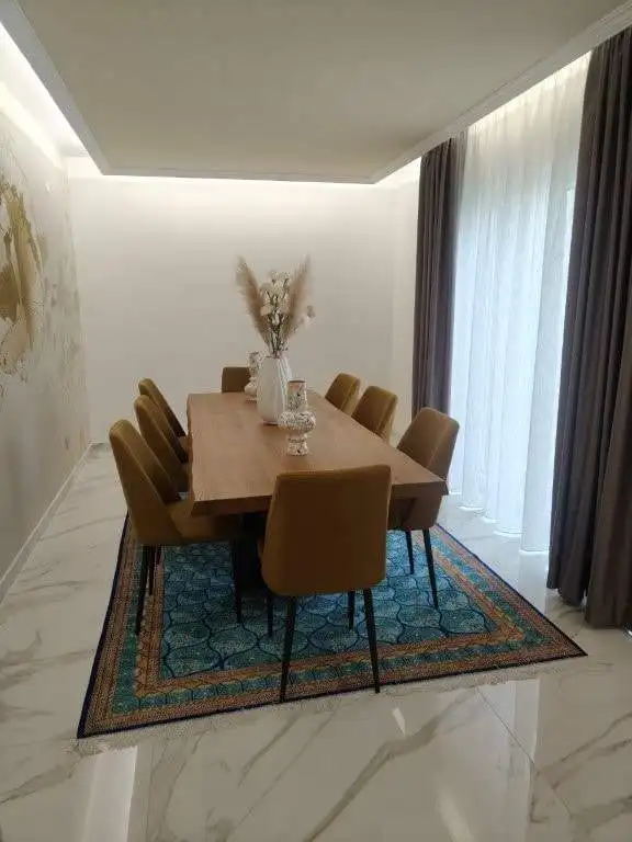Elegant dining room with a wooden table and eight chairs in a modern townhouse in Bernalda, Italy.
