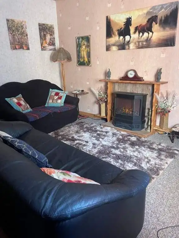 Interior of a comfortable living room featuring a fireplace, horse paintings, and plush sofas.