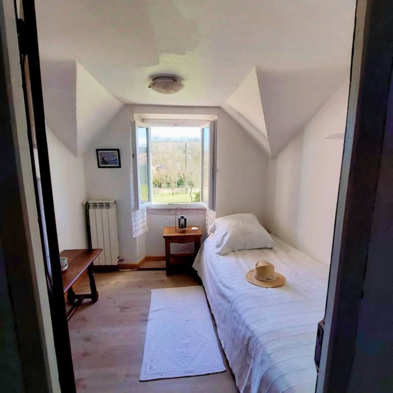 Interior view of a cozy farmhouse hallway in Madiran, France, with a door leading to a bright room.