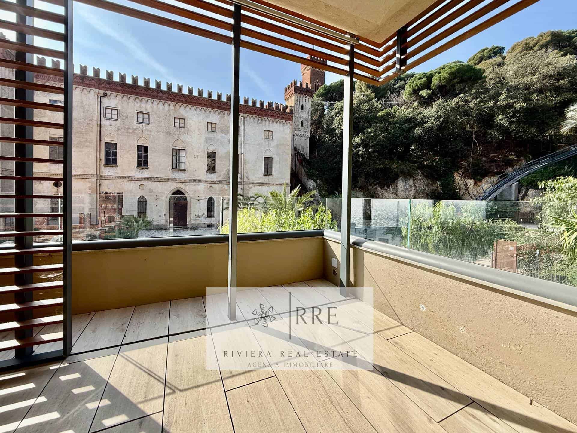 Balcony with view of historic castle and lush greenery in a scenic location.