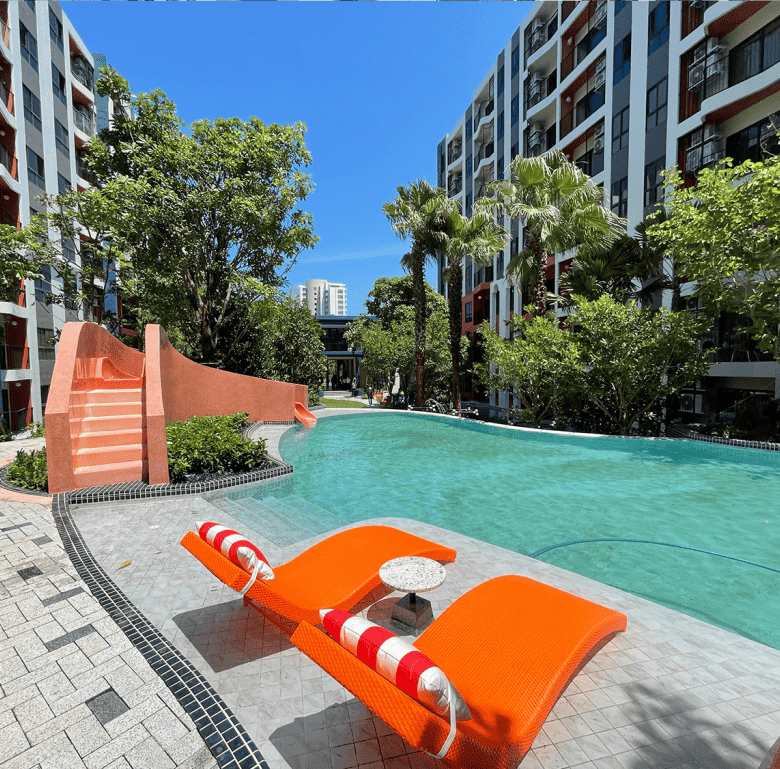 Beautiful outdoor pool area at Hua Hin cabanas, surrounded by lush greenery and modern apartment bui.