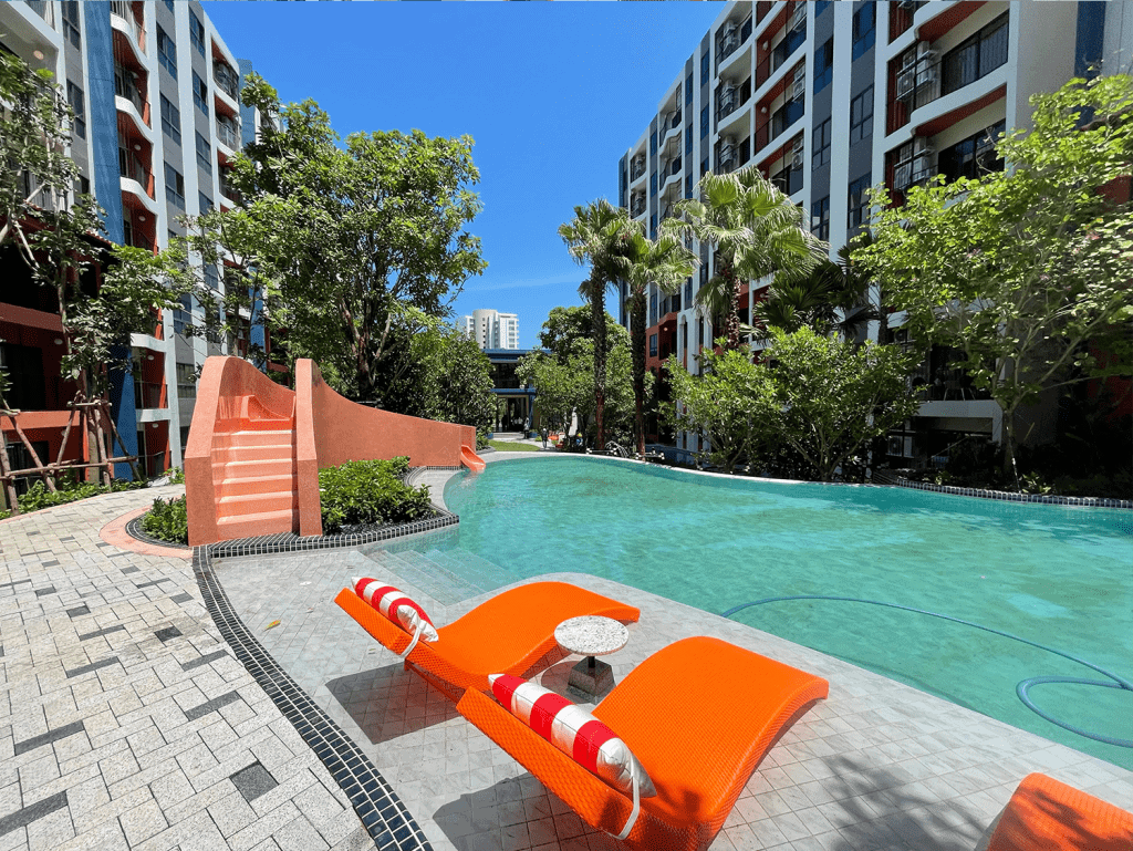 Beautiful outdoor pool area at Hua Hin cabanas, surrounded by lush greenery and modern apartment bui.