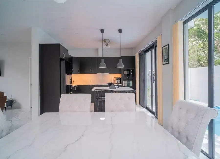 Modern kitchen and dining area in a luxury villa in The Orchard Golf and Country Club, Dasmarinas Philippines. Elegant kitchen with black cabinets and bright lighting.