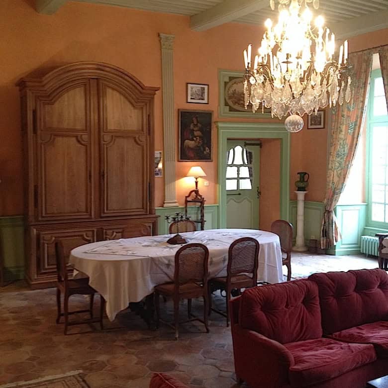 Château interior featuring antique furniture, chandelier, and classic decor in Thiers, France.
