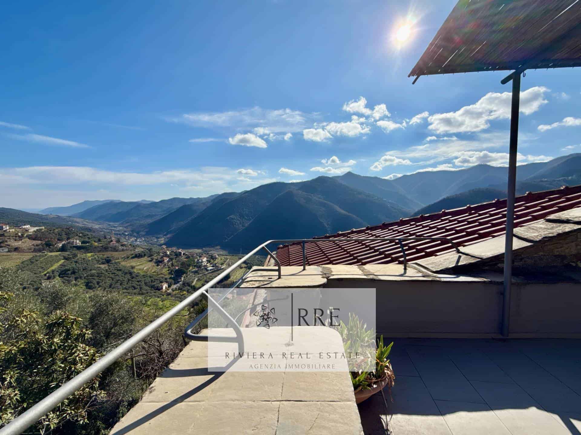 Scenic mountain view from a terrace overlooking lush hills and distant mountains under a clear blue.