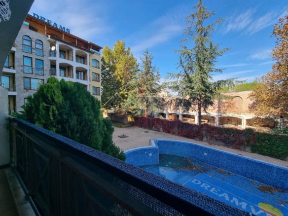 View of outdoor pool and lush greenery from balcony of 1-bedroom apartment in Sunny Beach.