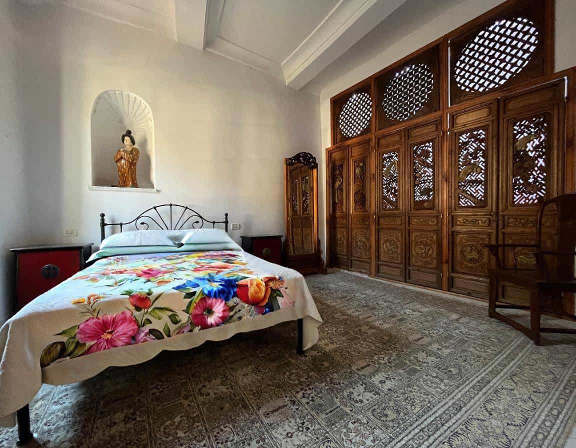 Traditional bedroom with ornate wooden furniture and floral bedspread.