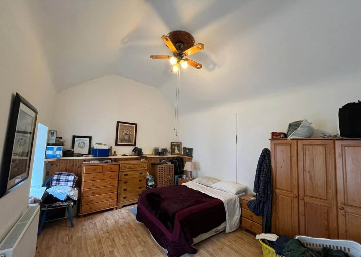 Bright bedroom with wooden furniture and a sloped ceiling in a charming Irish cottage.