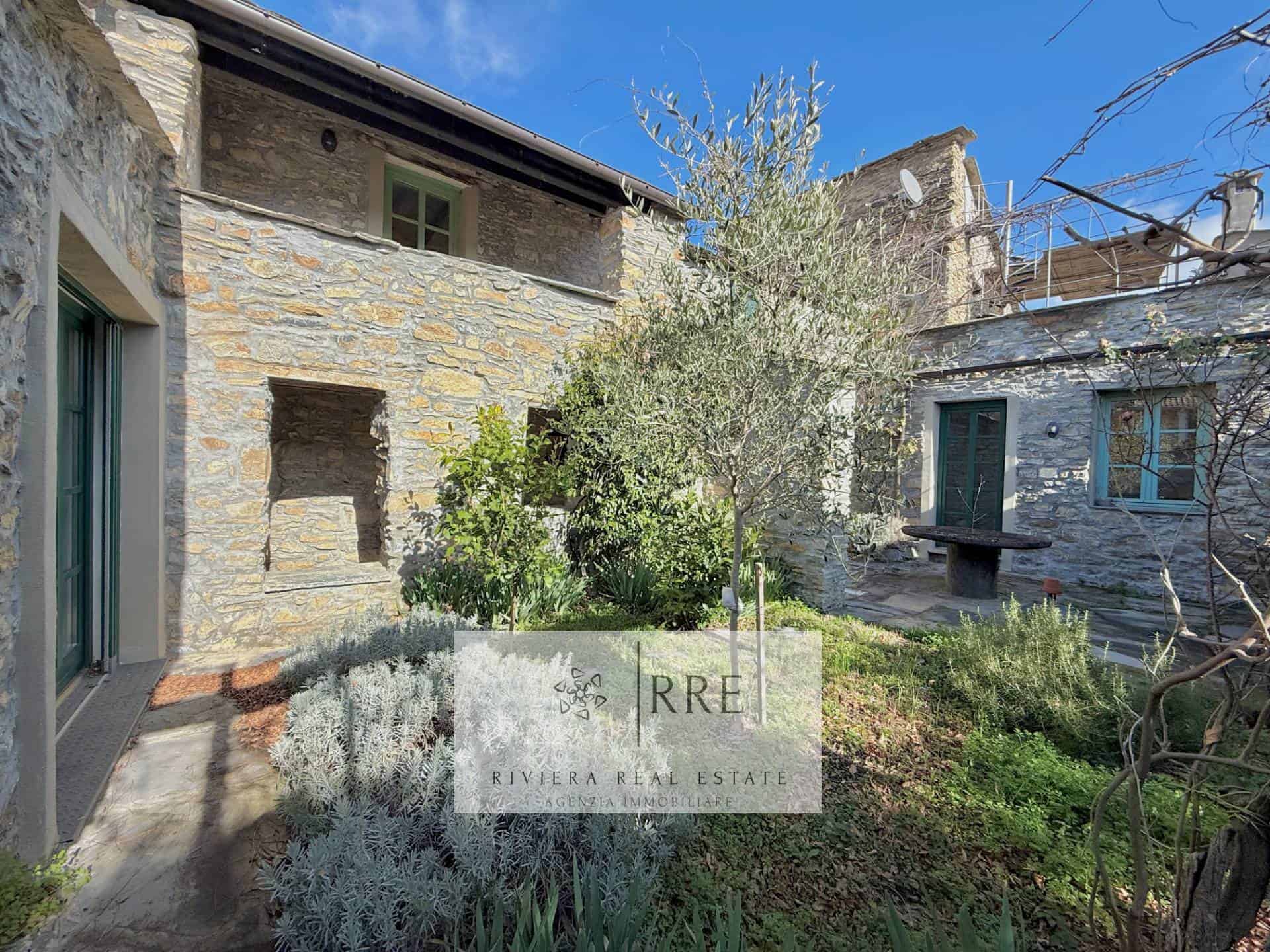 Stone house courtyard with lush greenery and rustic charm.