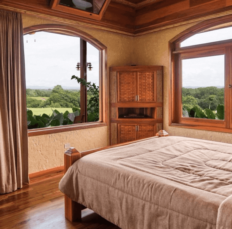 Bedroom with large windows overlooking lush green landscape in La Fortuna, Costa Rica.