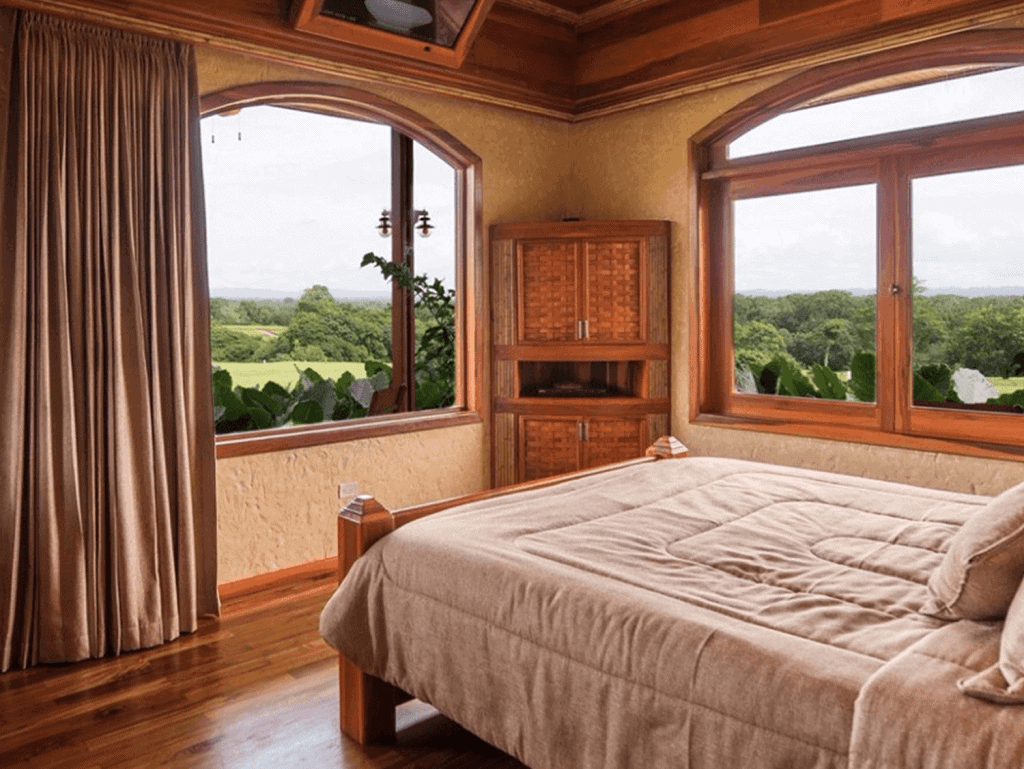 Bedroom with large windows overlooking lush green landscape in La Fortuna, Costa Rica.