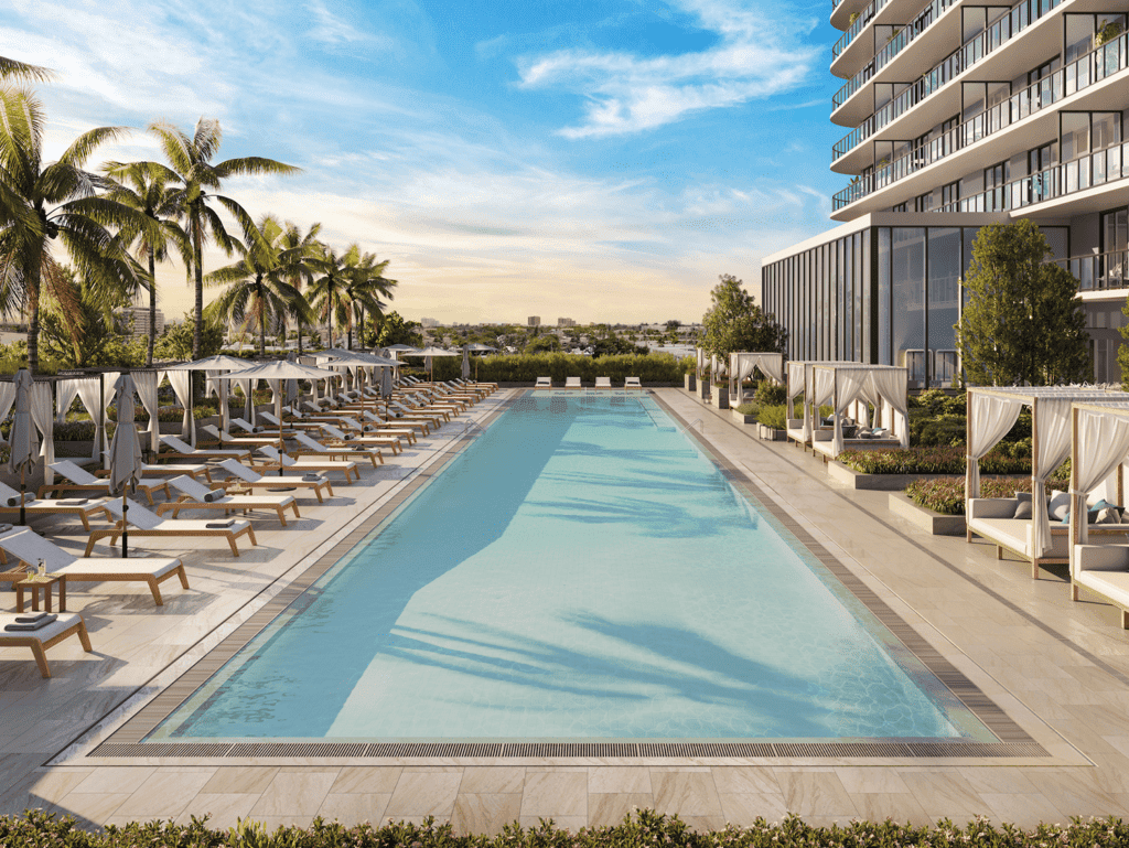 Modern hotel pool with palm trees and sun loungers in North Beach Miami, Florida.