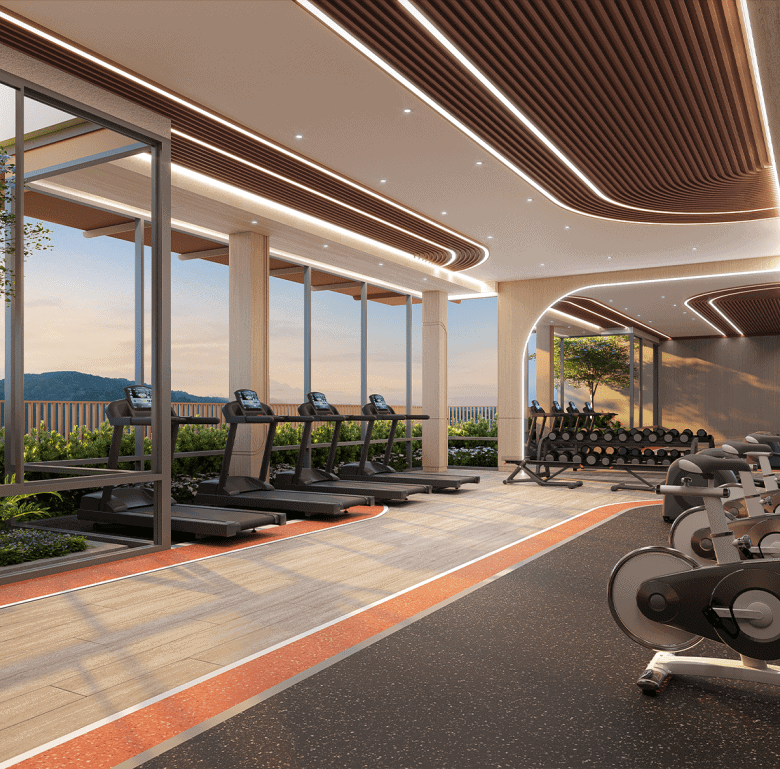 Gym interior with cardio equipment and large windows overlooking lush landscape in Phuket, Thailand.